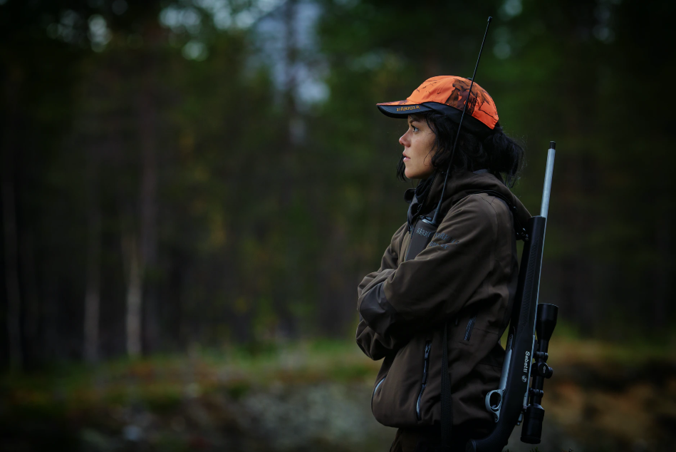 woman hunter with a.243 rifle and blaze orange cap
