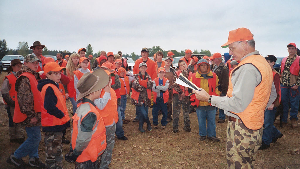 Staff Sgt. Micah VanDyke teaching gun safety to children in orange safety vests