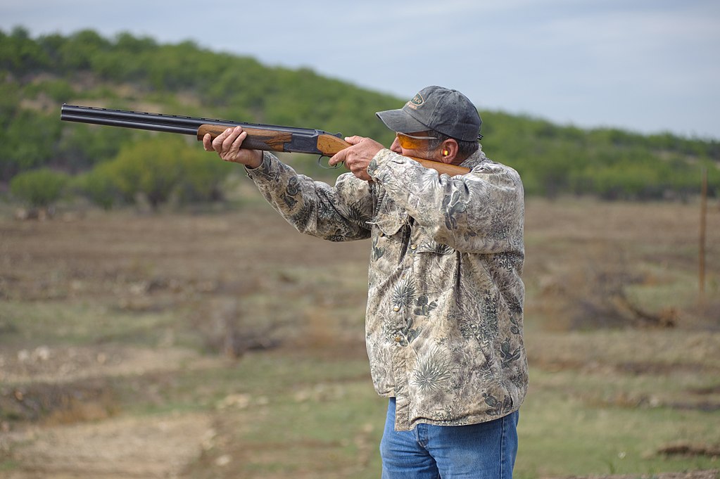 Hunter with a shotgun, eye, and ear protection and camouflage jacket