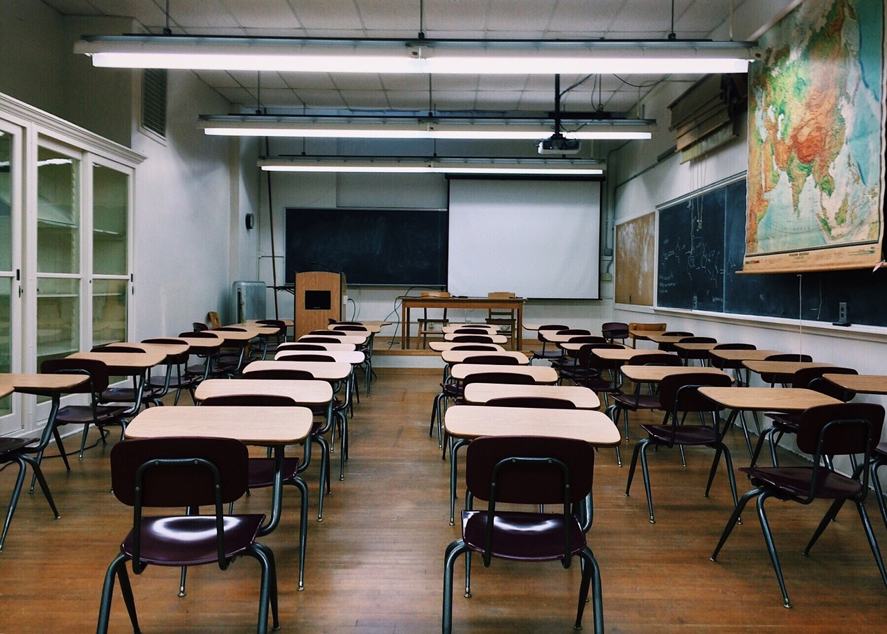 Empty classroom with black chairs attached to brown surface desks