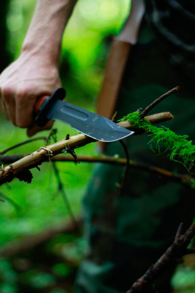 a man cutting a twig using a knife